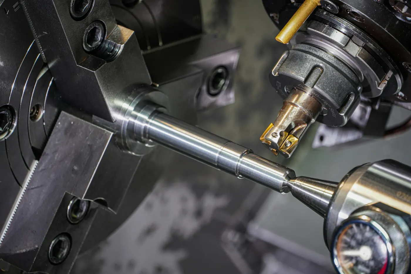 Nahaufnahme einer CNC-Drehmaschine: eine Welle im Spannfutter, daneben das Fräswerkzeug.